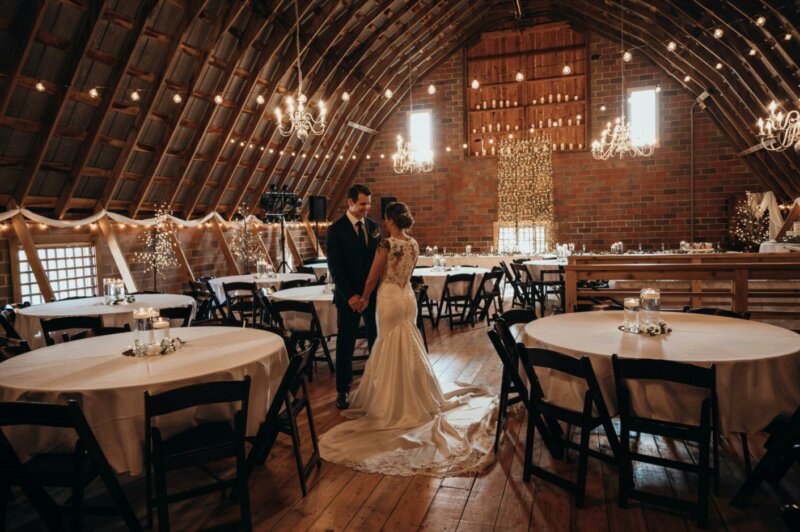 Married couple dancing in a rustic venue lit by candles