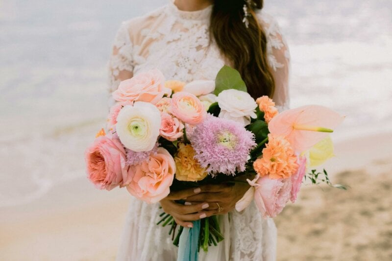 Mariée en robe en dentelle avec un gros bouquet de fleurs