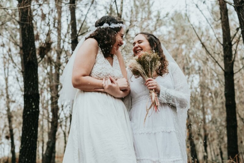 Couple de mariées dans la forêt en train de rire