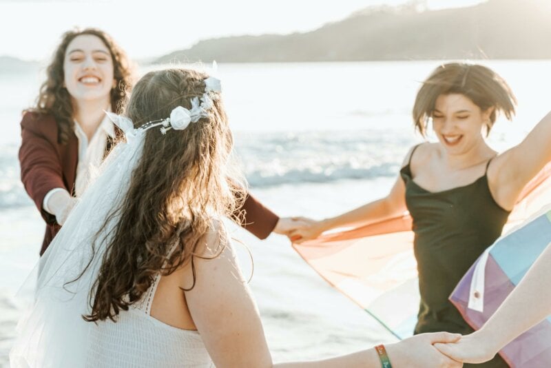 Mariées et invitées en train de danser sur la plage