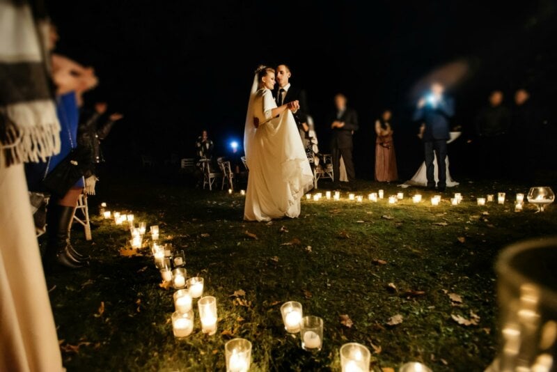 Couple de mariés en train de danser la nuit, entouré de bougies