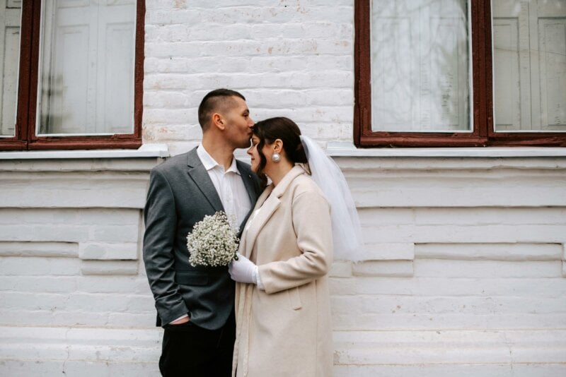 Married couple kissing in front of a building