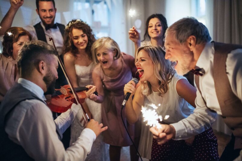 Invités et mariés en train de danser et chanter au son du violon