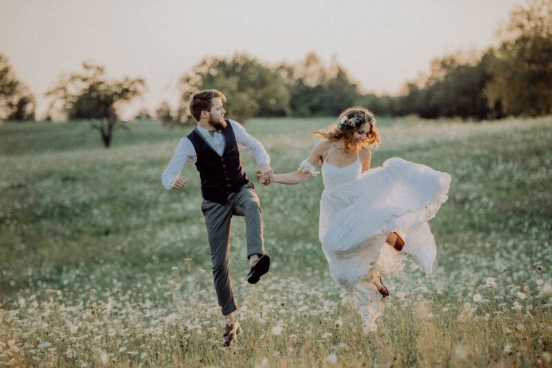 Jumping bride and groom in a field