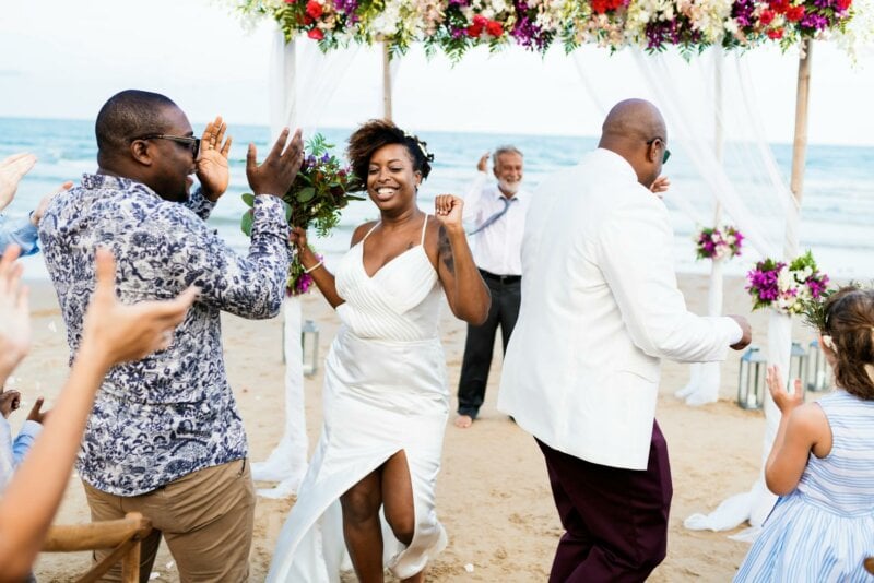 Couple de mariés et invités en train de danser sur une plage