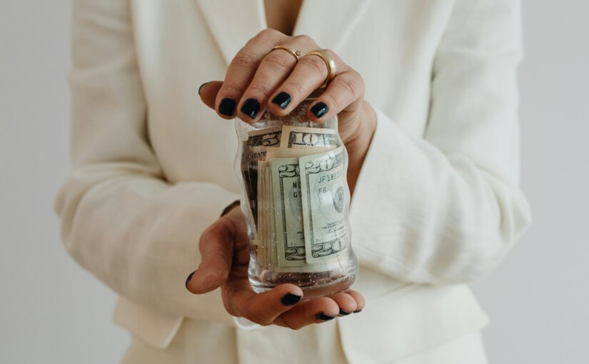 Bride wearing wedding and engagement rings holding a jar of money