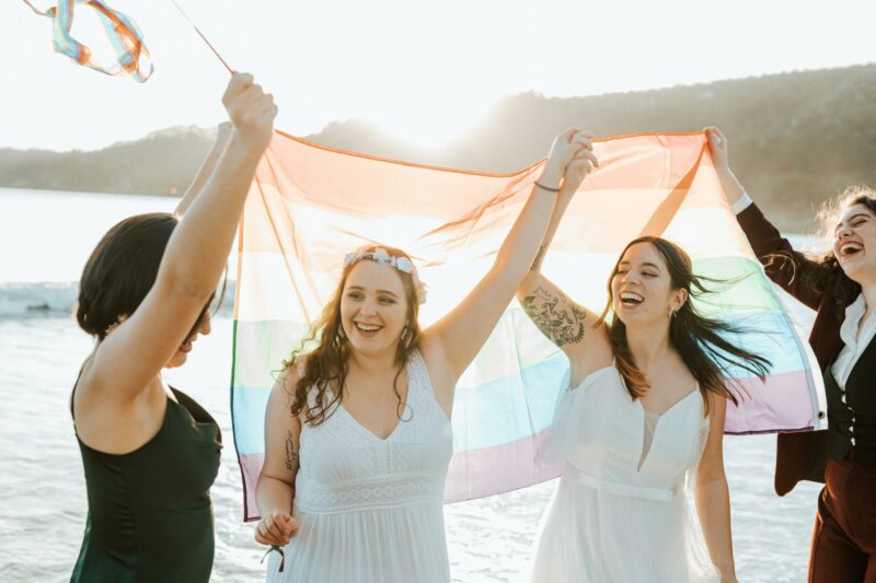 Couple de mariées et témoins avec un drapeau LGBTQ