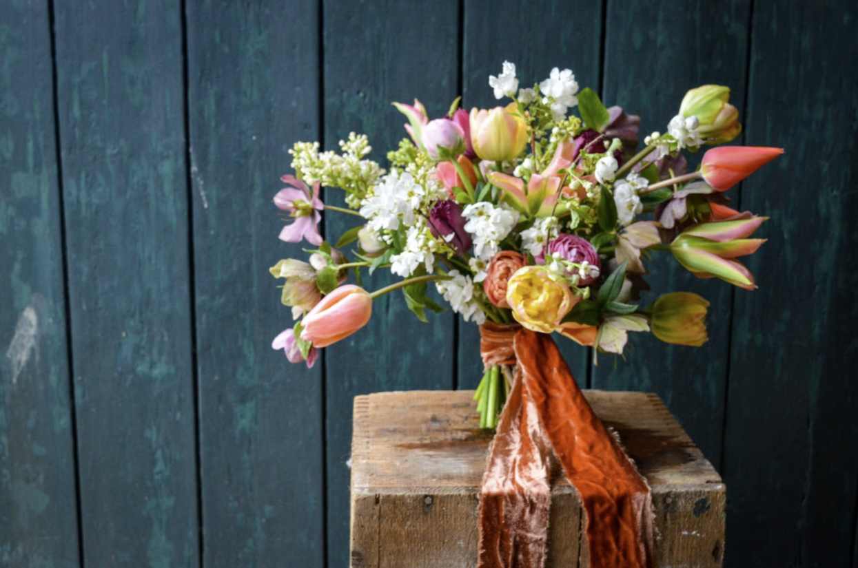 Multi-coloured wedding bouquet tied together with a piece of orange velvet material 
