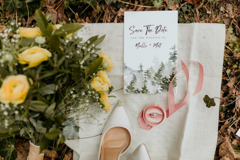 Wedding details shot of save the date, shoes, ring and flowers