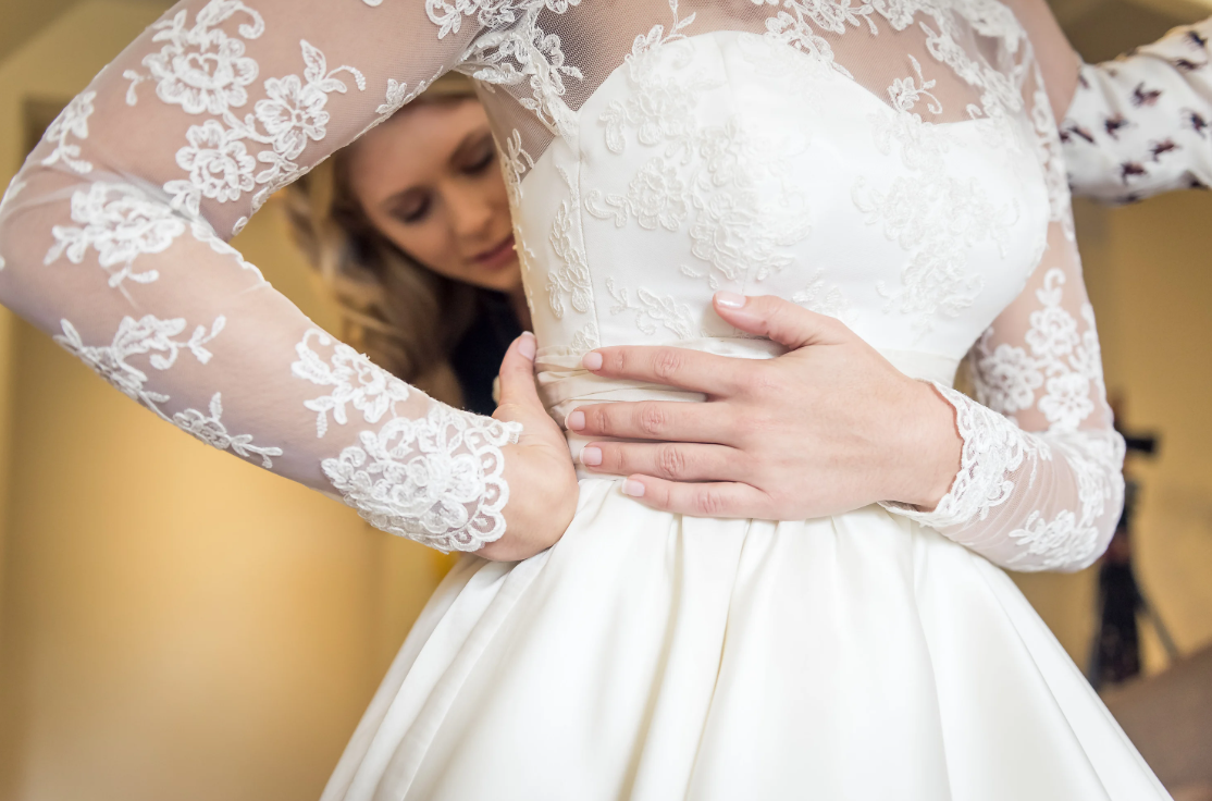 Bride getting zipped up into her wedding dress