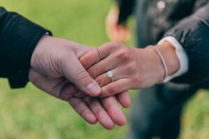Engaged couple holding hands, showing engagement ring