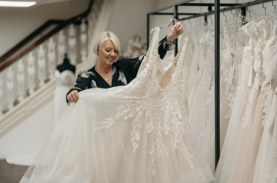 Shop assistant picking a wedding dress of the rail
