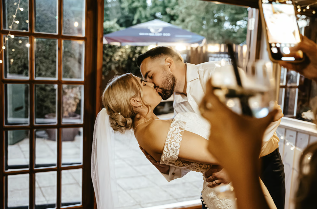 Candid still of a newly wedded couple kissing in a low dip captured by a wedding videographer