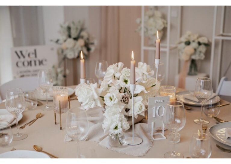 Elegante Hochzeit Tischdeko in Weiß mit Kerzen, goldenen Besteckdetails und floraler Blumendekoration