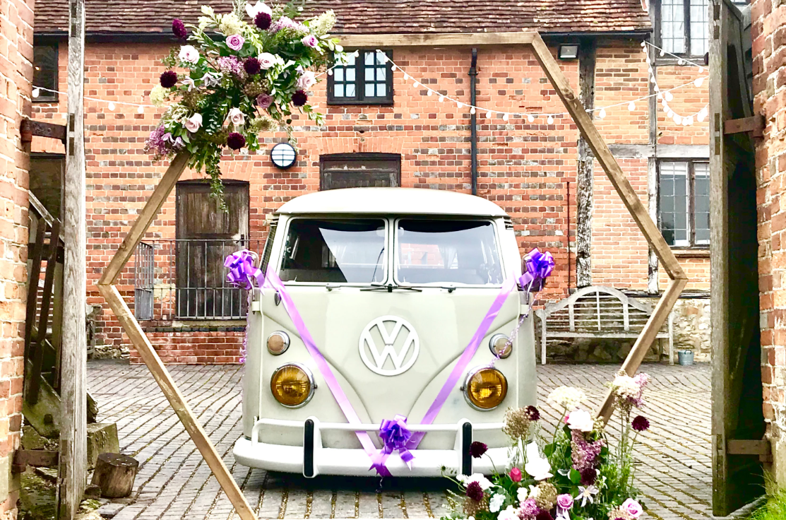 A sage wedding campervan decorated with purple ribbons