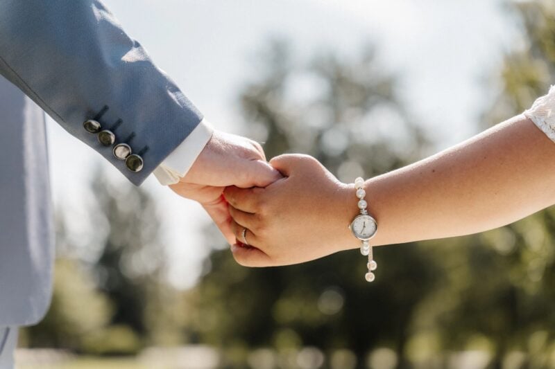Detailaufnahme der Hände von Braut und Bräutigam bei der freien Trauung im Sonnenlicht