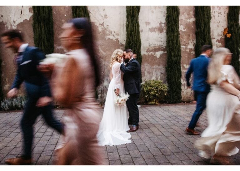 Hochzeitspaar im Fokus, es laufen Gäste verschwommen im Bild um sie