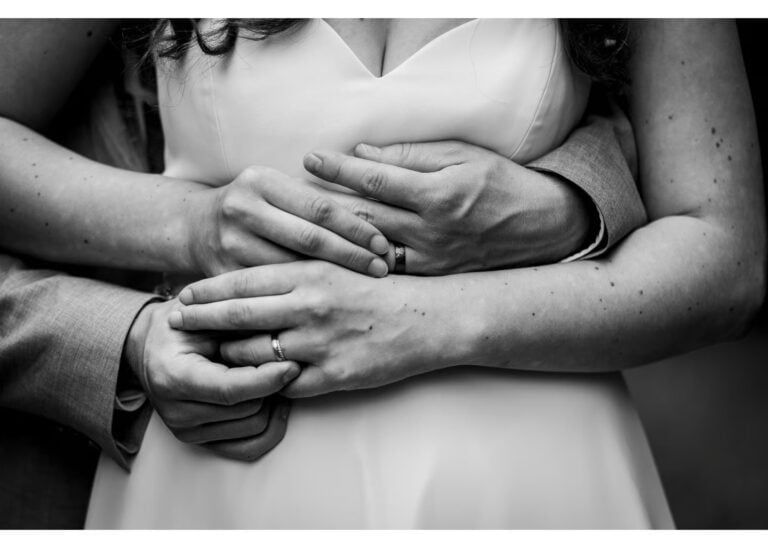 Brautpaar in inniger Umarmung mit sichtbaren Eheringen – Schwarz-weiß Hochzeitsfoto