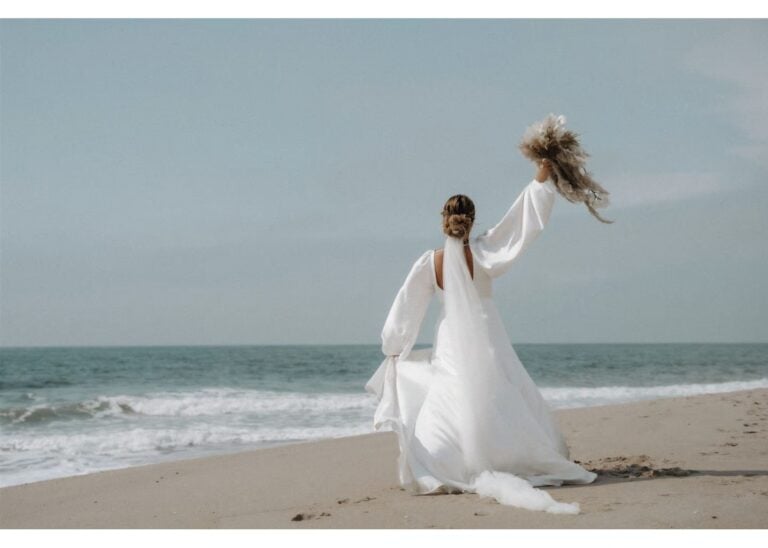 Braut in fließendem Brautkleid bei einer romantischen Strandhochzeit am Meer
