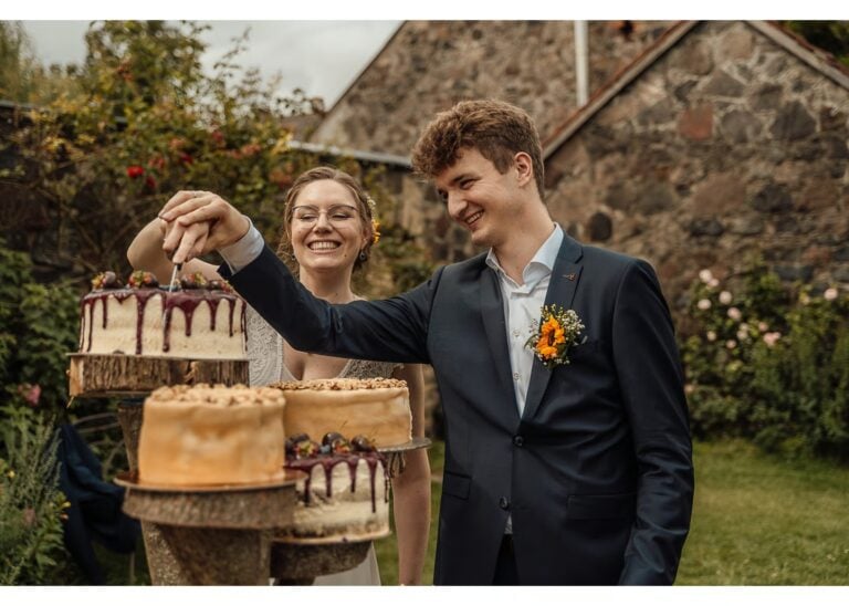 Glückliches Paar schneidet Hochzeitstorte an