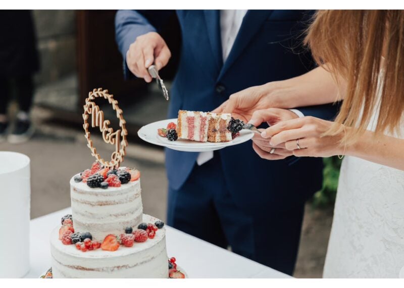 Detailaufnahme eines Paares beim Anschneiden der Hochzeitstorte