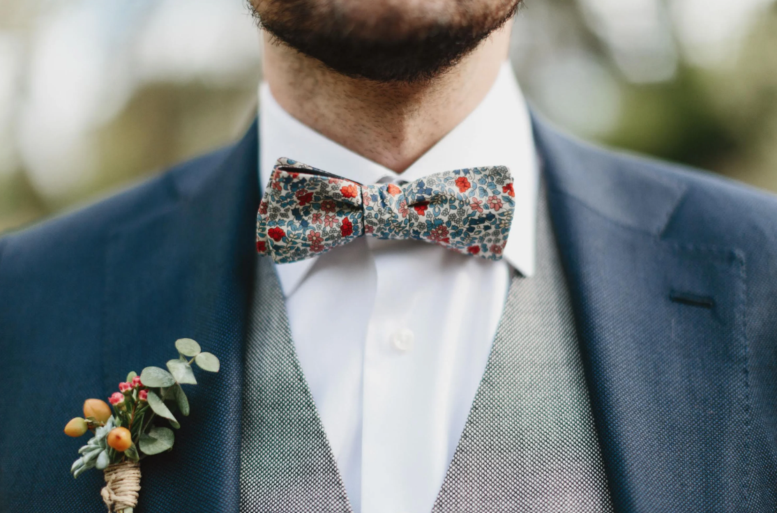 close up shot of groom with floral bow tie