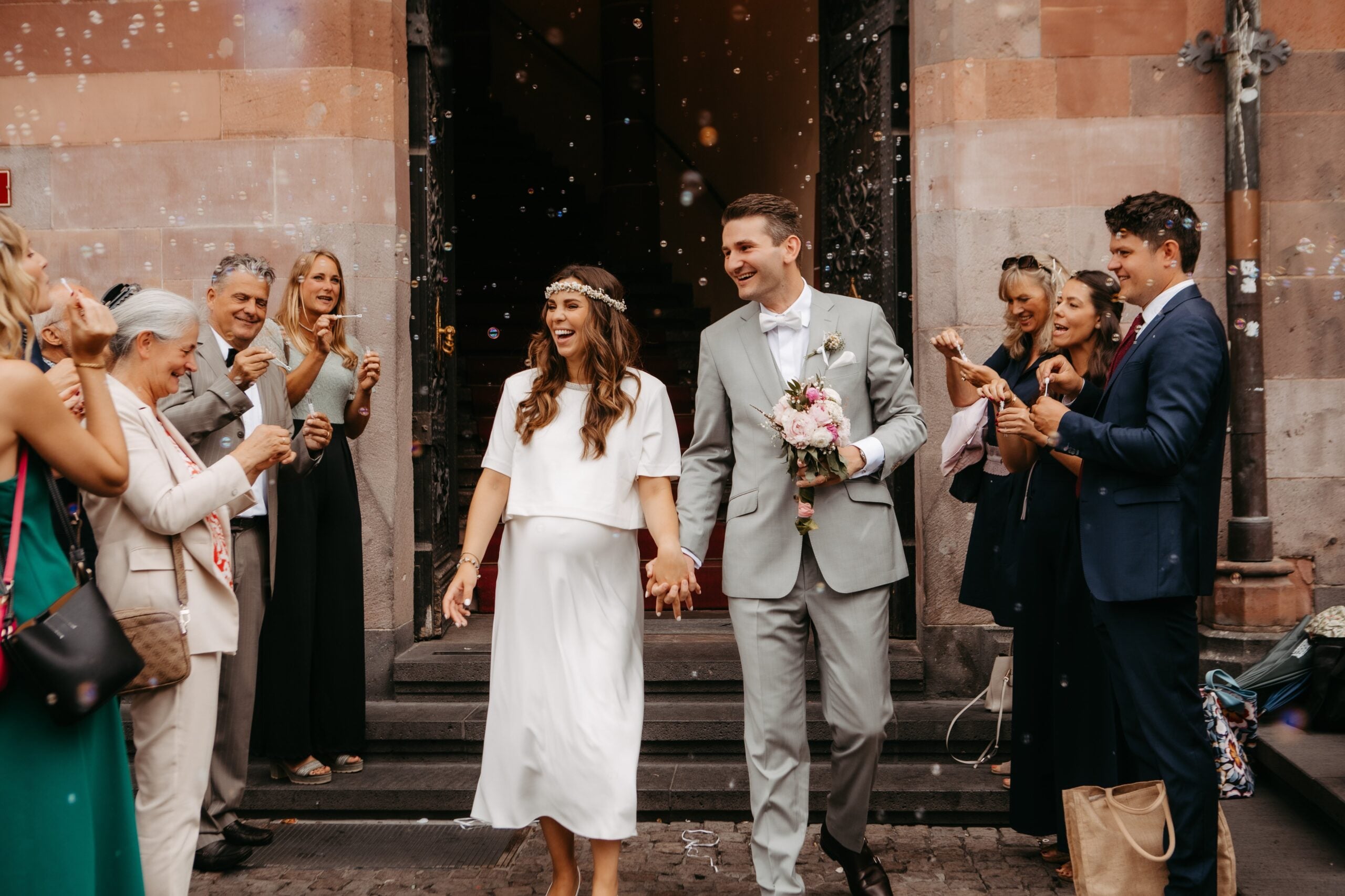 Glückliches Paar wird von Gästen nach der Zeremonie in Empfang genommen