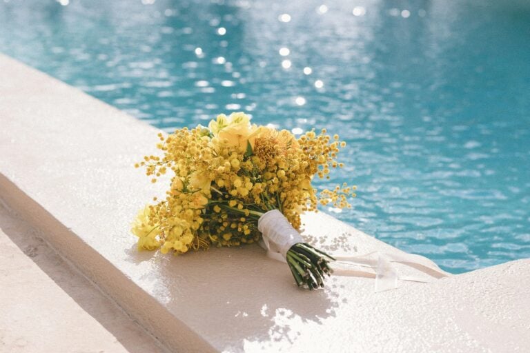 Gelber Brautstrauß liegt am Rand eines Pools bei einer Sommerhochzeit