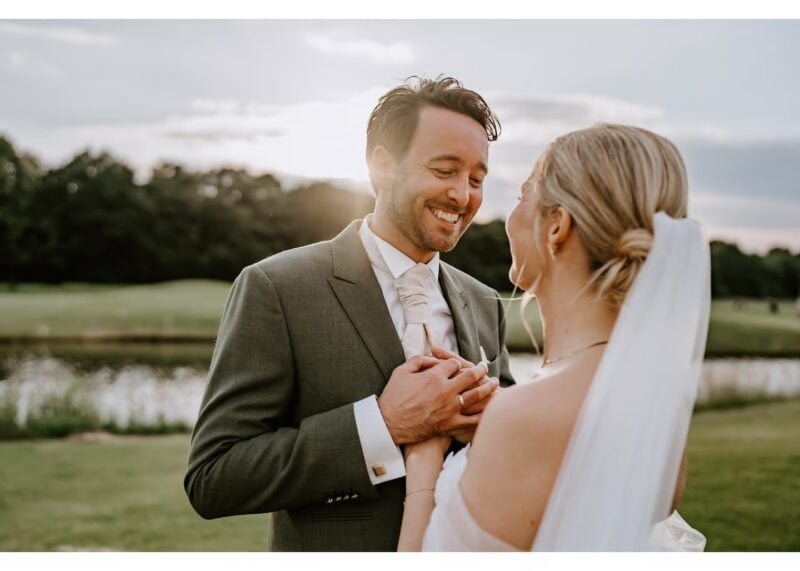 Braut und Bräutigam halten sich lächelnd die Hände bei einer Outdoor-Hochzeit