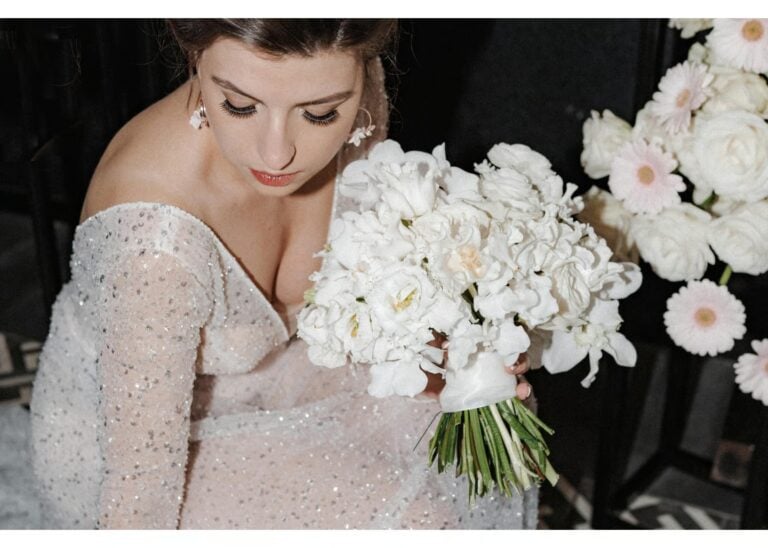 Braut hält einen weißen Blumenstrauß und blickt nach unten