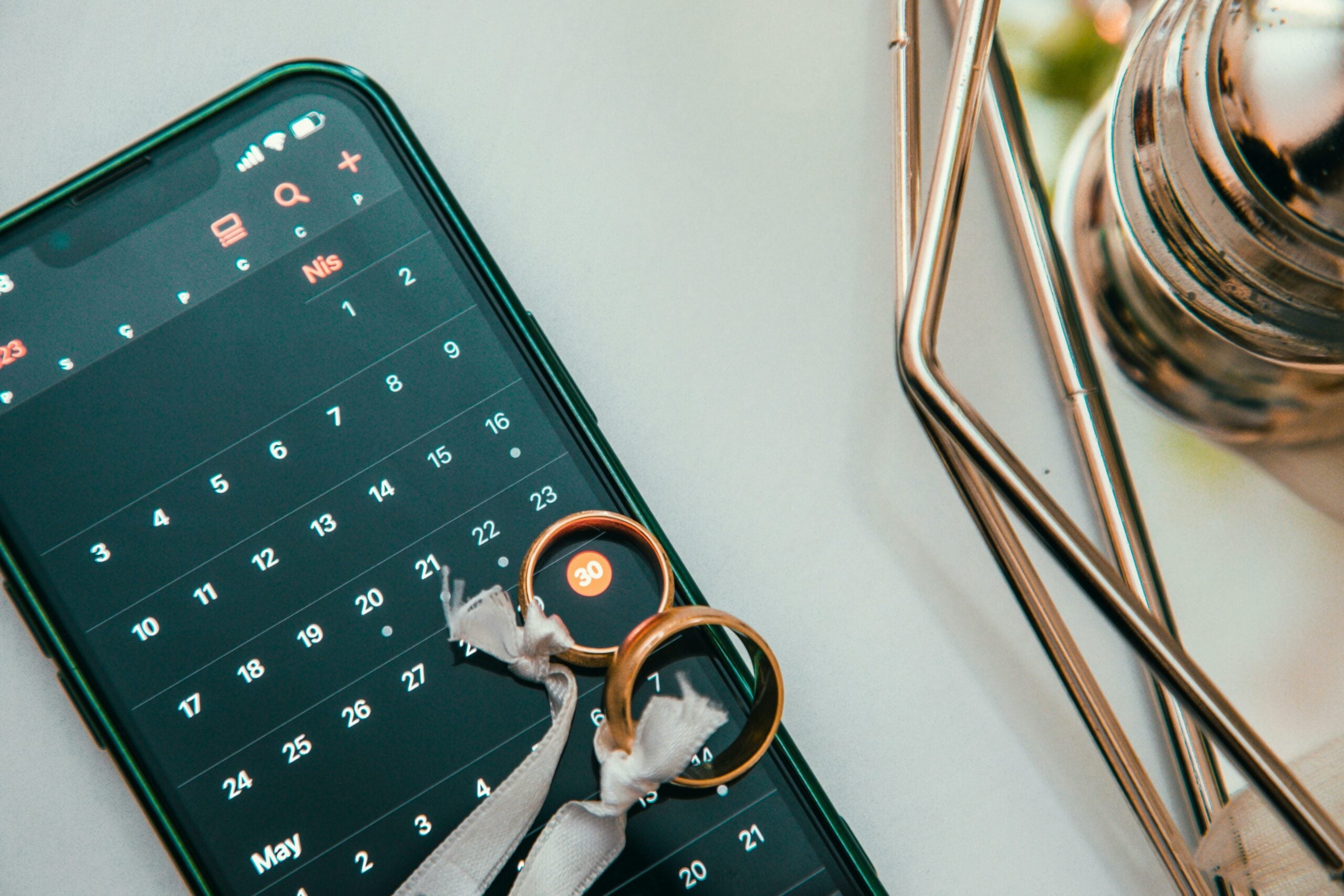 Two wedding rings placed on a mobile phone screen showing a calculator