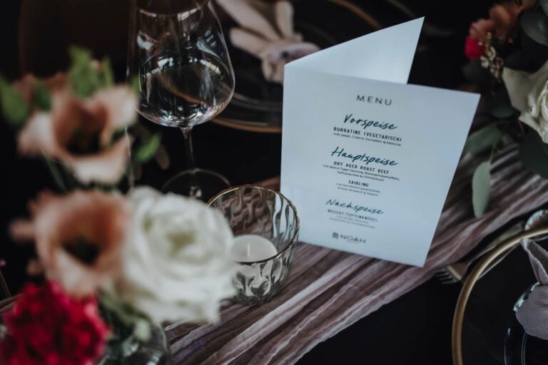 Elegante Menükarte für die Hochzeit auf stilvoll dekoriertem Tisch mit Kerze und Blumen