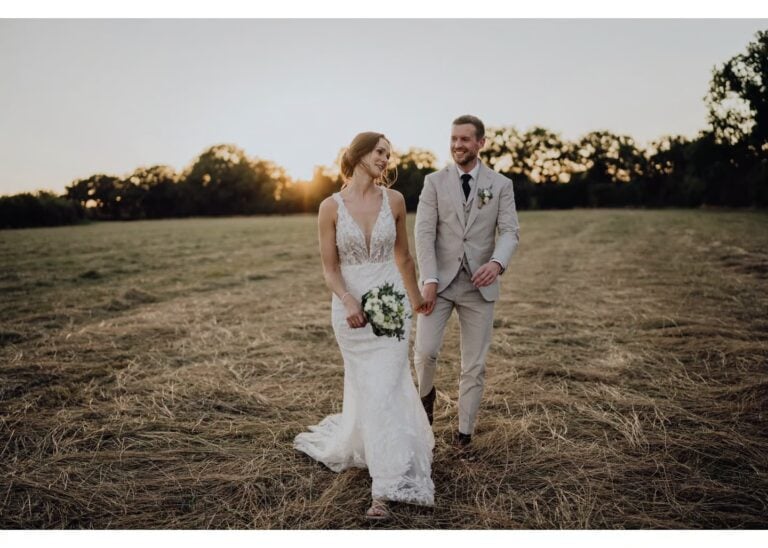 Brautpaar geht Hand in Hand über ein Feld bei Sonnenuntergang
