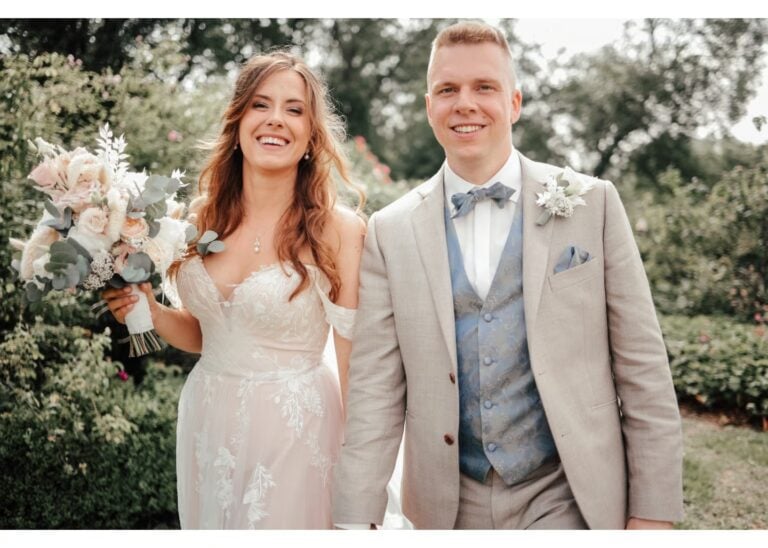 Glückliches Brautpaar läuft Hand in Hand durch einen Garten nach der Hochzeit