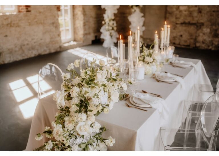 Elegante Hochzeitstafel mit weißen Blumen und Kerzen in einer hellen Location