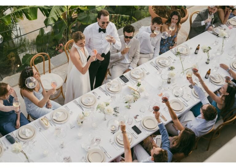 Hochzeitsgäste stoßen gemeinsam mit dem Brautpaar am festlich gedeckten Tisch an