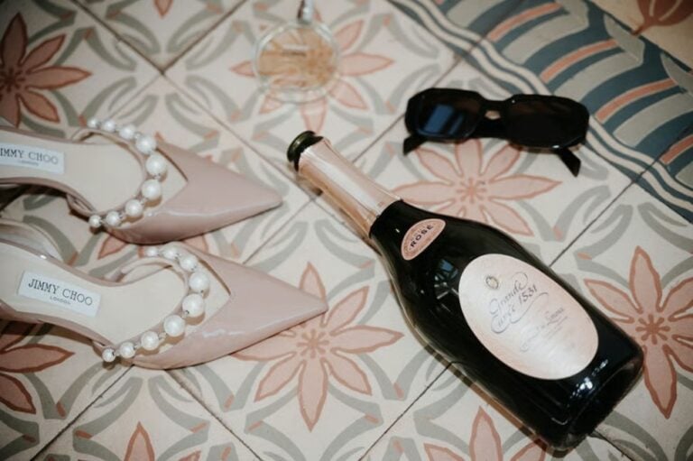 Brautschuhe, Sonnenbrille und eine Flasche Rosé-Champagner liegen auf dem Boden
