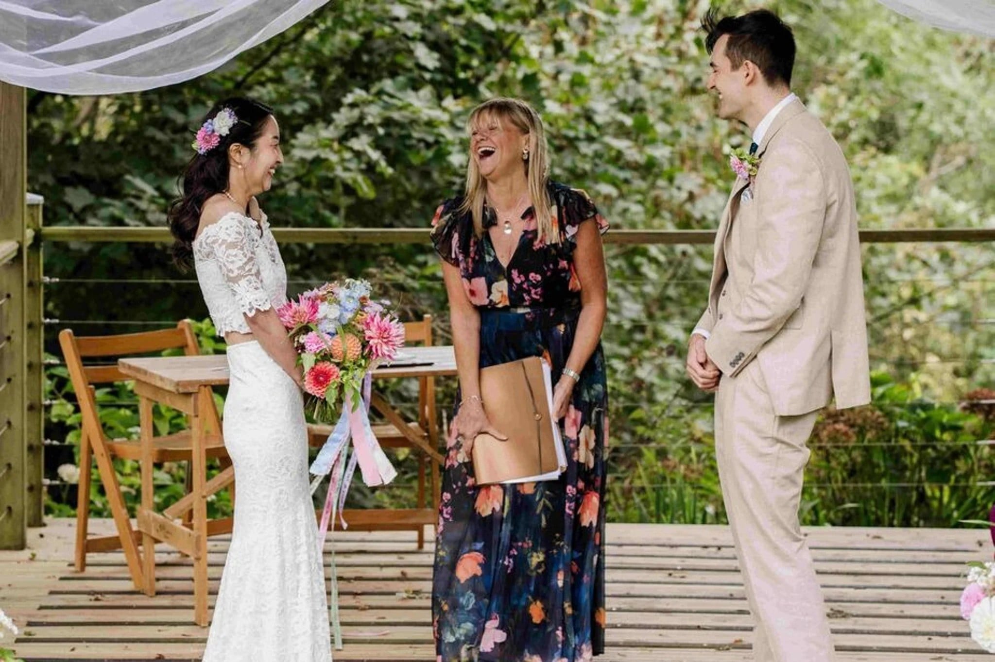 A celebrant laughing during an outdoor wedding ceremony