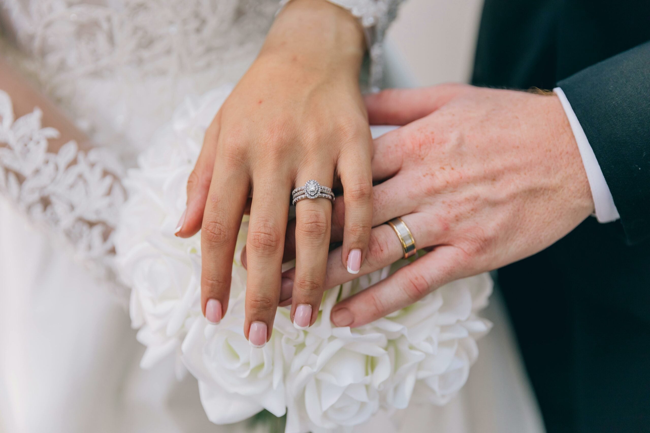 A bride and groom's hands displaying their wedding rings