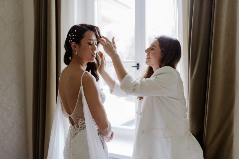 Braut beim Getting Ready während eine Stylistin die Hochzeitsfrisur vorbereitet