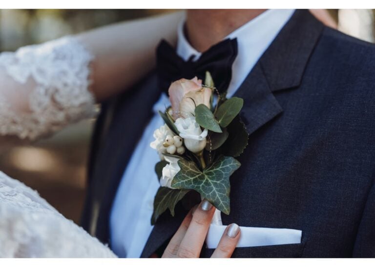 Braut richtet die Ansteckblume am Anzug des Bräutigams