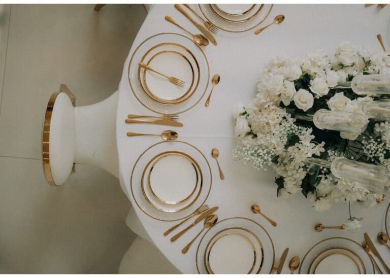 Elegante Hochzeits-Tischdekoration mit weißen Blumen und goldenen Tellern