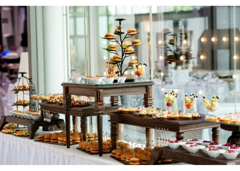 Modernes Hochzeitsbuffet mit Fingerfood, Mini-Burgern und Desserts auf stilvoll dekorierten Tischen