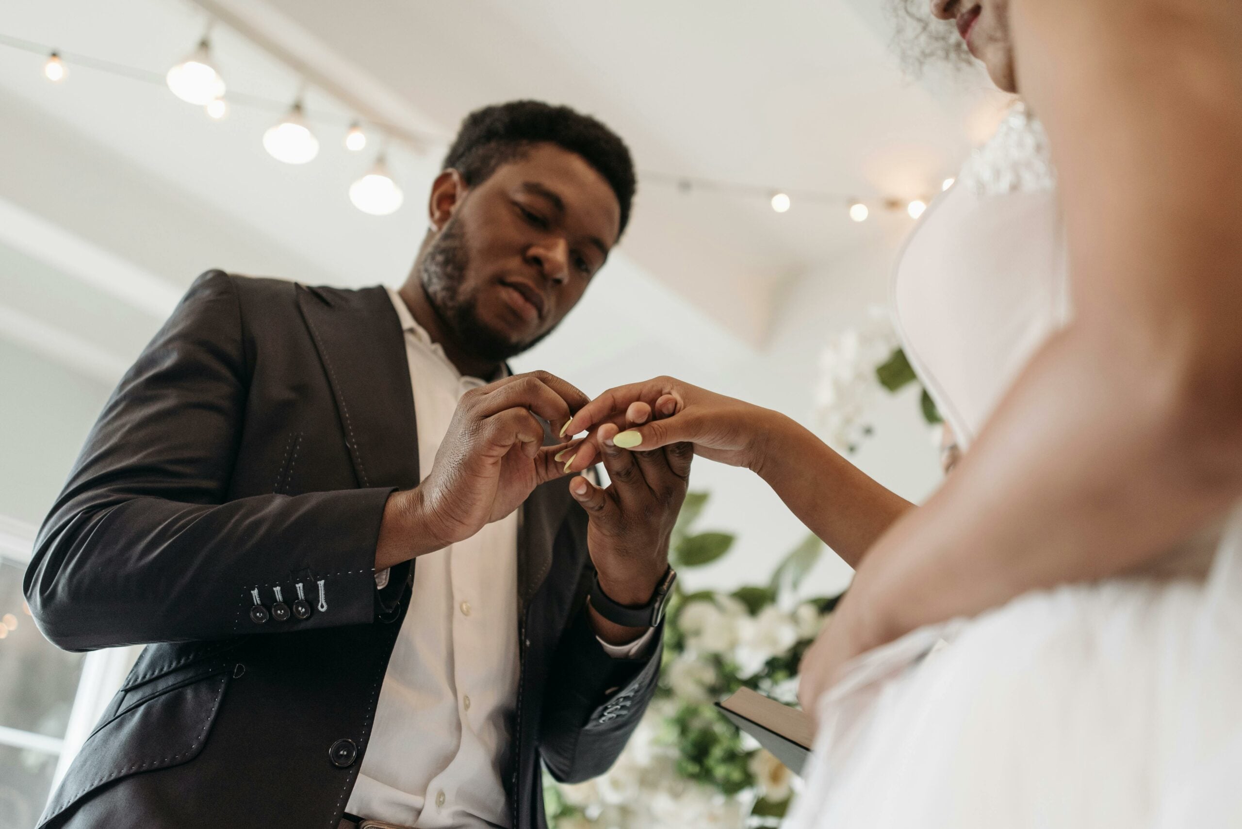 A groom placing a ring on the bride's hand during a wedding ceremony
