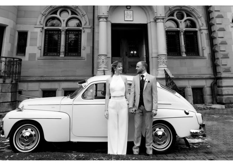 Brautpaar steht Hand in Hand vor einem klassischen Oldtimer vor einer Villa