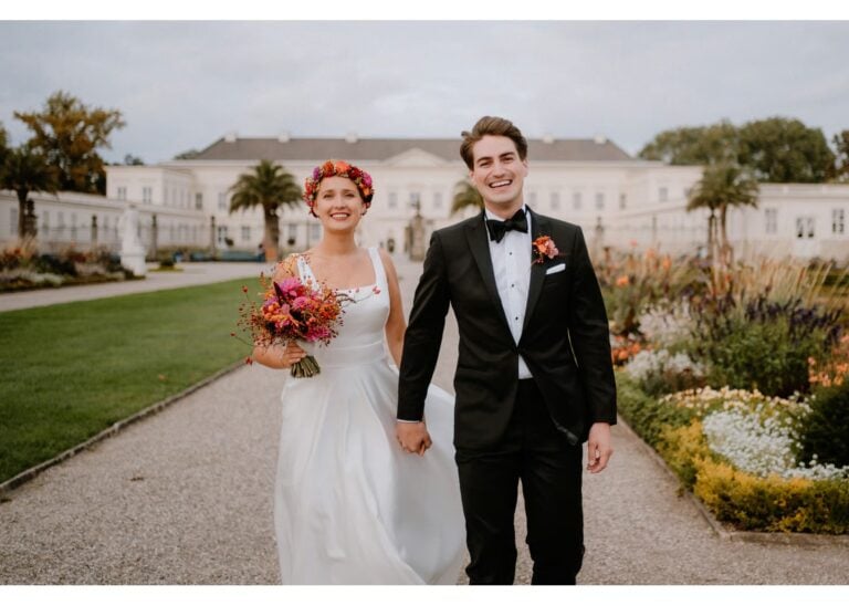 Brautpaar läuft Hand in Hand durch einen Schlossgarten