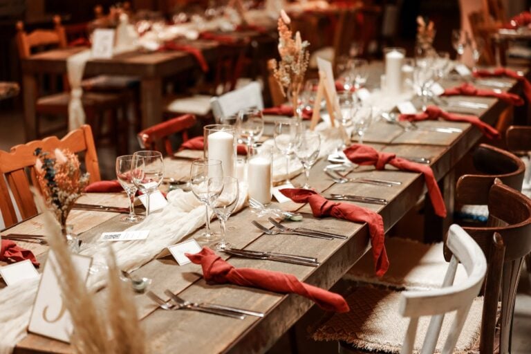 Rustikale Hochzeits-Tafel mit Kerzen, Gläsern und roten Servietten