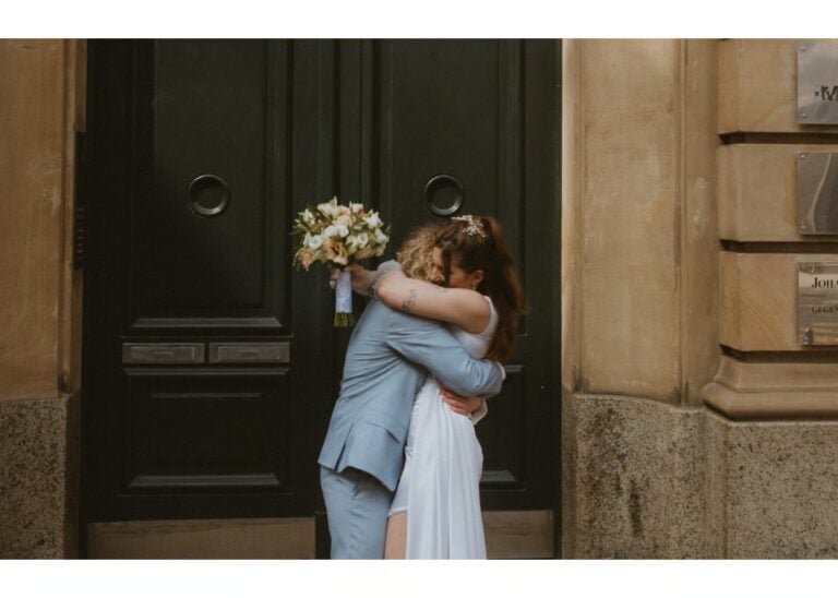 Ehepaar umarmt sich vor einer großen Tür nach der Trauung