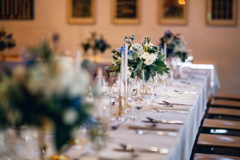 Elegante Hochzeitstafel mit weißer Tischwäsche, Kerzen und floraler Tischdekoration