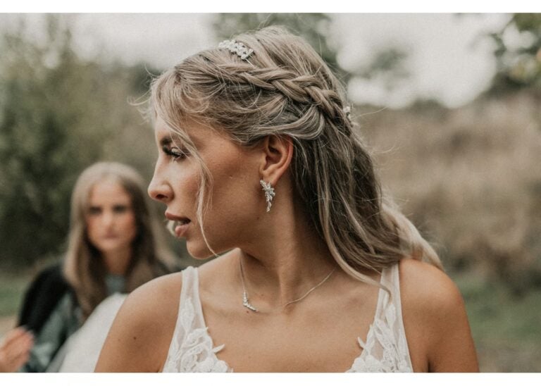 Braut mit geflochtener Hochzeitsfrisur und Schmuck während der Hochzeitsvorbereitungen